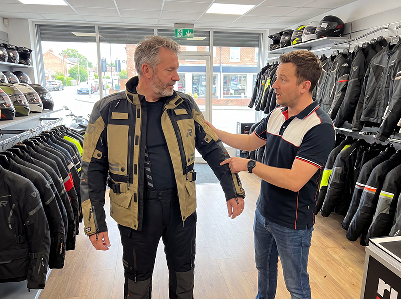 Man in motorcycle apparel store being fitted with laminated motorcycle jacket